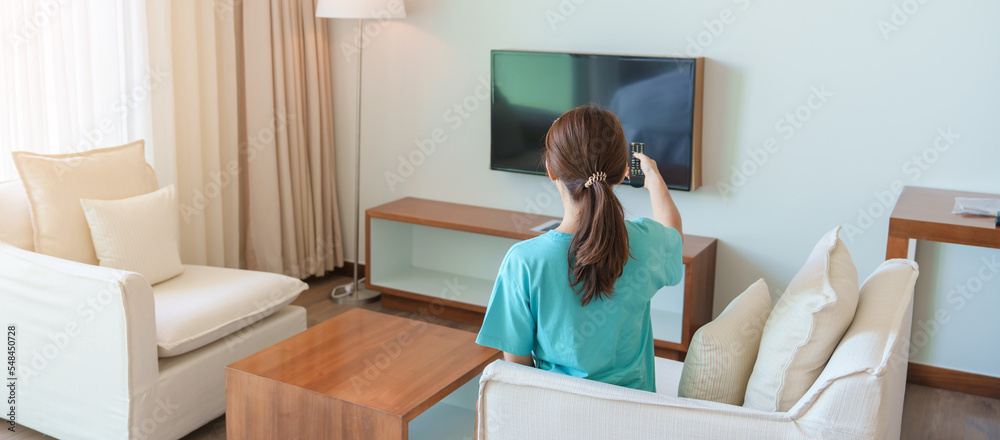 Woman relaxing on the couch, Girl using remote control and choosing TV show and movie series during rest on sofa in the morning. Apartment living concept Woman relaxing on the couch, Girl using remote control and choosing TV show and movie series during rest on sofa in the morning. Apartment living concept