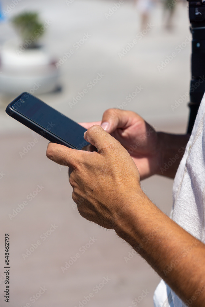 Hands of unrecognizable young man using mobile phone