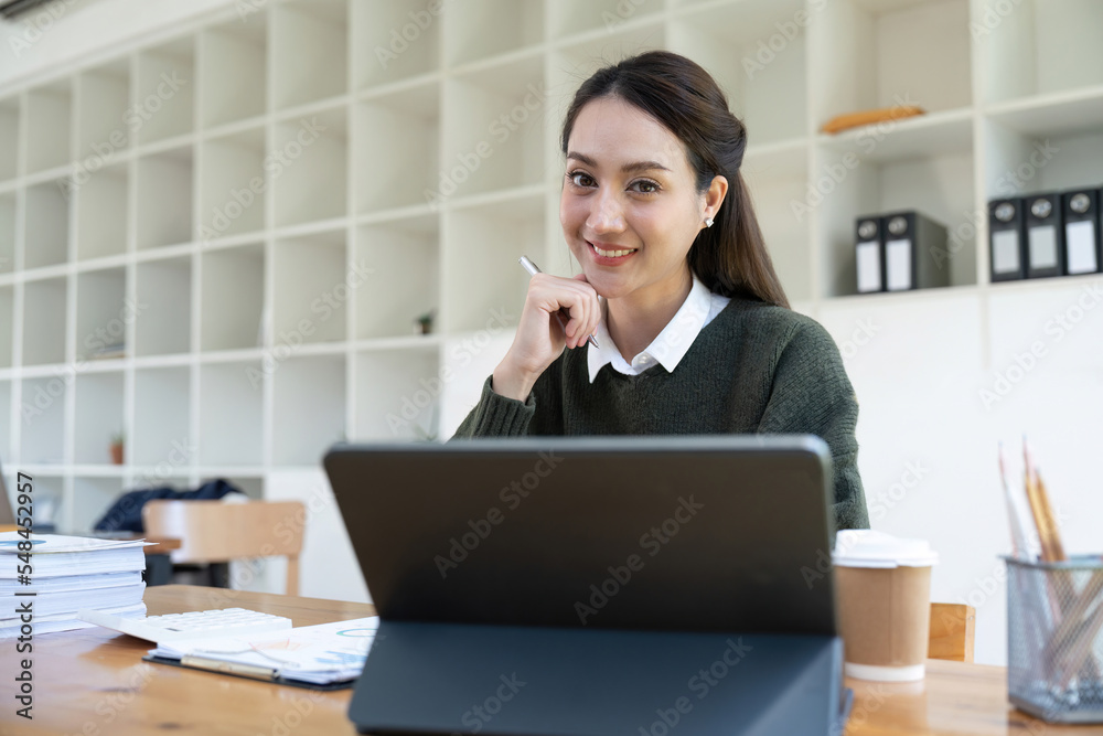 Portrait of smiling asian woman using laptop computer for financial paperwork analysis. Portrait of smiling asian woman using laptop computer for financial paperwork analysis.