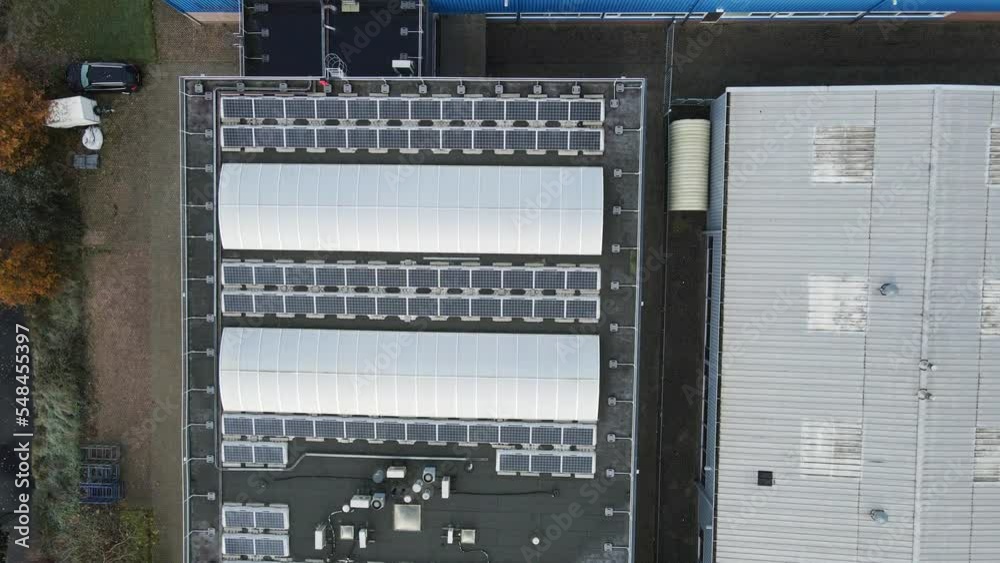 Top down aerial of rooftops filled with solar panels on industrial site