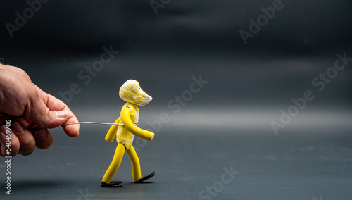 Stopmotion process of walking. Man's hand holding with an aluminum wire a figure made with yellow modeling paste starting the process of walking. The 12 principles of animation. photo