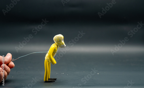 Stopmotion process of jumping. Preparing to jump. Man's hand holding with an aluminum wire a figure made with yellow modeling paste starting the jumping process. The 12 principles of animation. photo