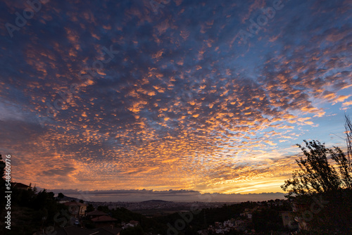 Golden sunrise on altocumulus clouds over houses photo