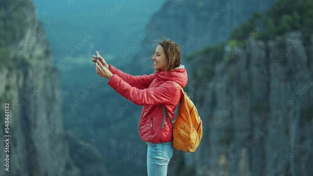hiker at view point of Tazi Canyon. A girl takes pictures of stunning canyon landscape on her smartphone. Happy woman on top of cliff enjoying mountain view, hike in famous touristic place in Turkey.