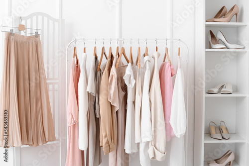 Rack with trendy clothes near light wall in dressing room