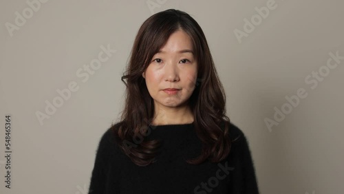 Middle aged asian woman opens her face and stares the camera. Emotionless, Protest, Unsatisfied.
