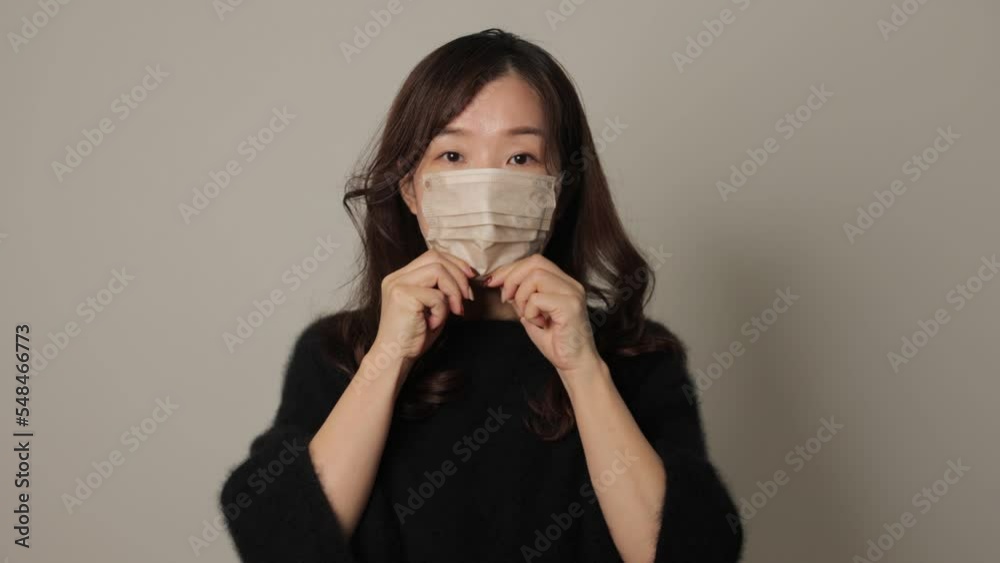 Asian woman put face mask on reluctantly. White background. Asian woman put face mask on reluctantly. White background.