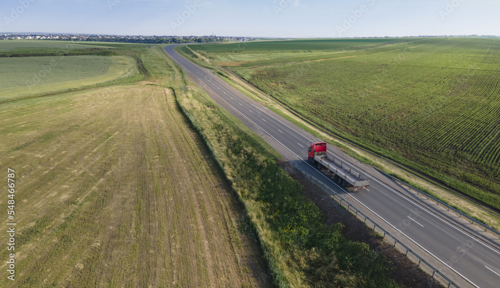 Red tipper truck on street road highway transportation. Semi-truck countryside aerial view.