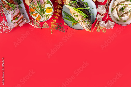 Fototapeta Naklejka Na Ścianę i Meble -  Traditional Chinese lunar New Year dinner table, party invitation, menu background with pork, fried fish, chicken, rice balls, dumplings, fortune cookie, nian gao cake, noodles, chinese decorations