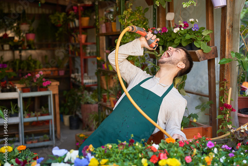 Fotobehang Florist in flower shop has fun singing with garden hose