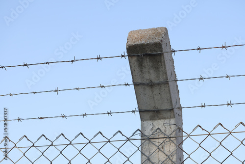 Security barbedwire fence, wire with clusters of short, sharp spikes on concrete pillar