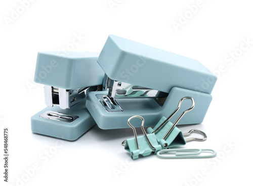 Office staplers and paper clips on white background
