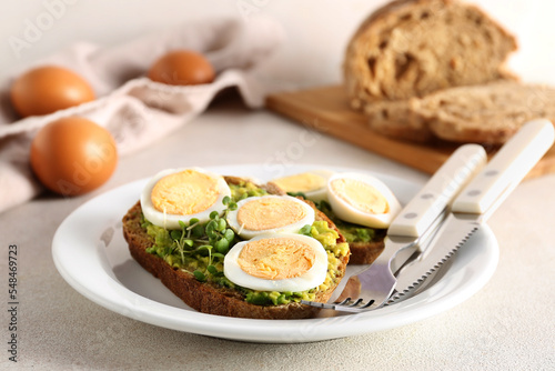 Plate of tasty toasts with boiled egg on light table  closeup