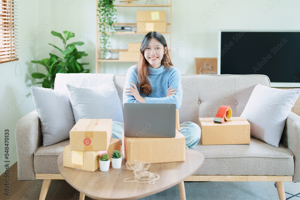 Starting small business entrepreneur of independent Asian woman smiling using computer laptop with cheerful success of online marketing package box items and SME delivery concept Starting small business entrepreneur of independent Asian woman smiling using computer laptop with cheerful success of online marketing package box items and SME delivery concept