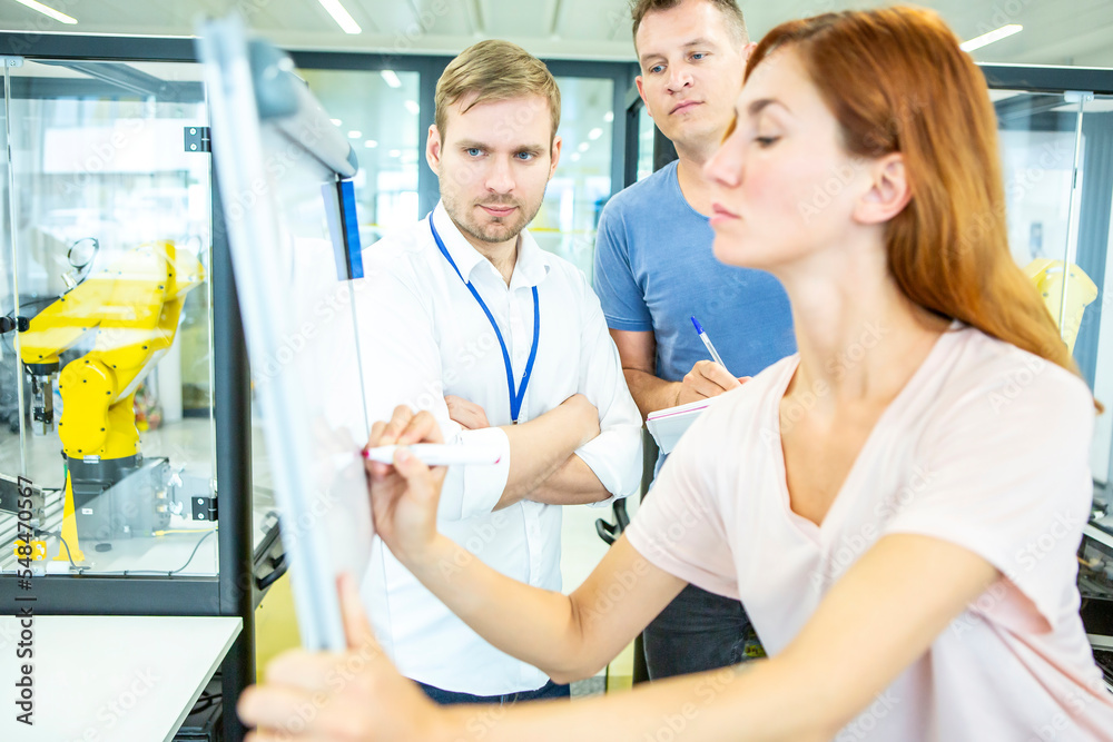 Fototapeta premium Die Mitarbeiter werden an dem Einsatz von Industrierobotern ausgebildet