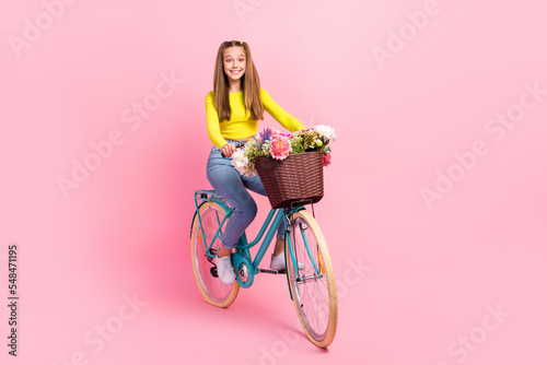 Full length photo of funky cute schoolgirl wear yellow crop top riding bike isolated pink color background © deagreez