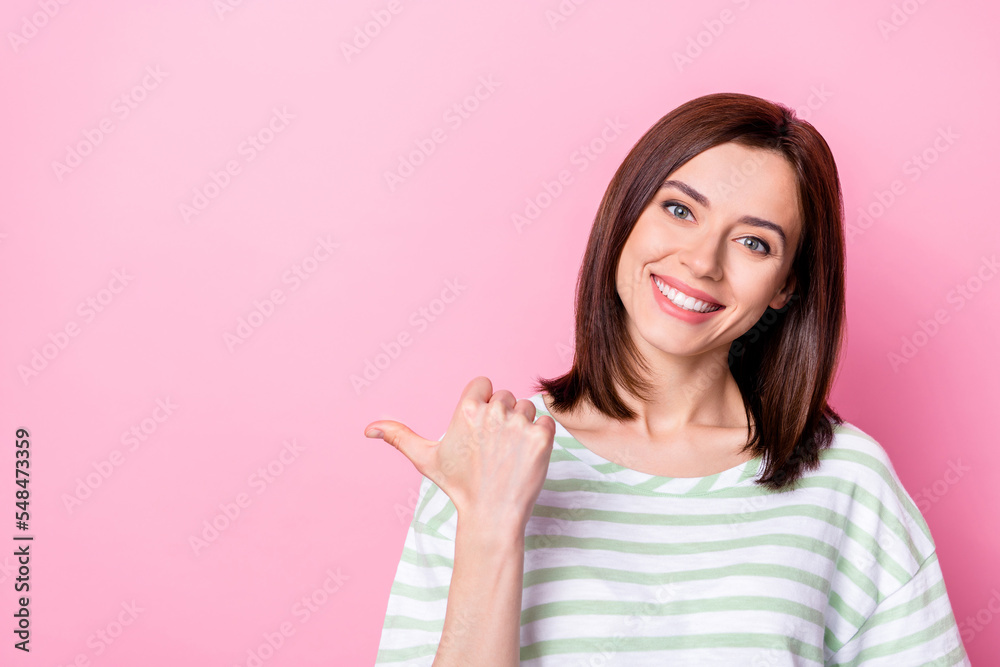 Portrait of nice cheerful woman with brunette hairstyle dressed striped t-shirt indicating empty space isolated on pink color background Portrait of nice cheerful woman with brunette hairstyle dressed striped t-shirt indicating empty space isolated on pink color background
