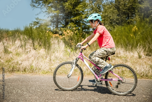 outdoor portrait of a white happy girl riding a bike on natural background. High quality photo