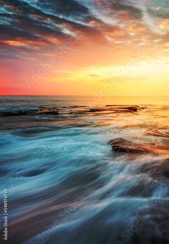 Incoming waves wash over rocks at sunrise