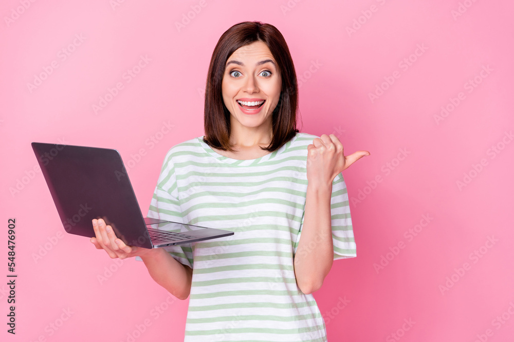 Photo portrait of adorable young lady work remotely point banner offer space wear trendy striped outfit isolated on pink color background Photo portrait of adorable young lady work remotely point banner offer space wear trendy striped outfit isolated on pink color background