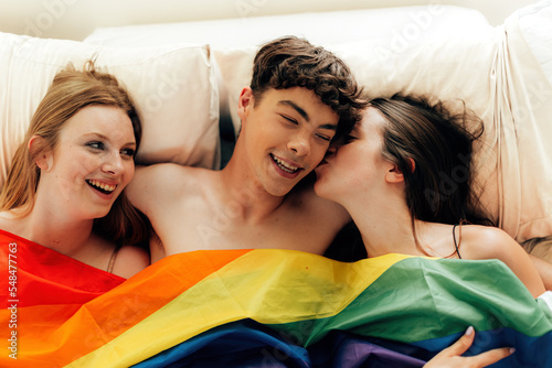 polyamory of young people engage in multiple romantic relationships - male and female threesome under a rainbow flag