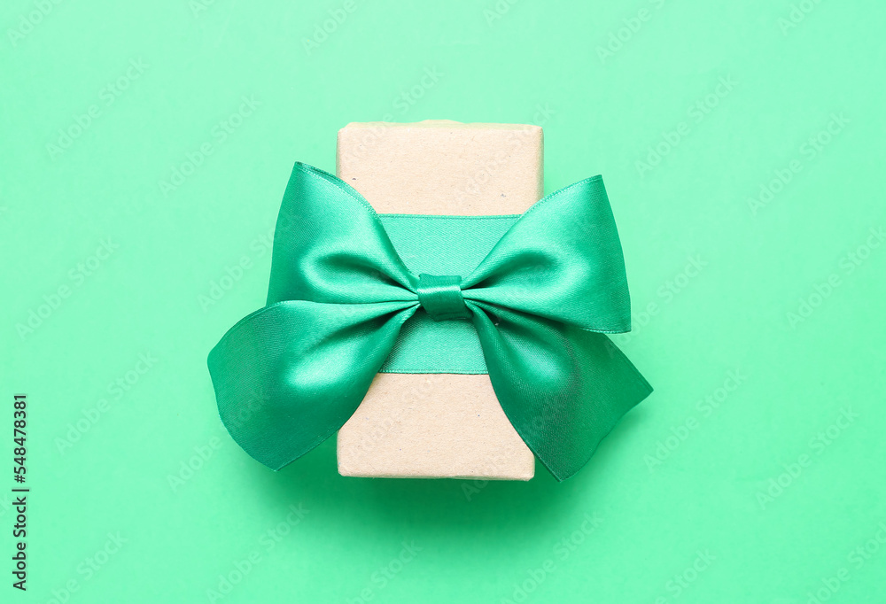 Christmas gift box with bow on green background