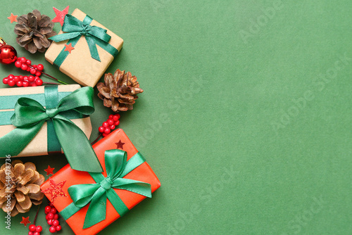 Christmas gift boxes with rowan and fir cones on green background © Pixel-Shot