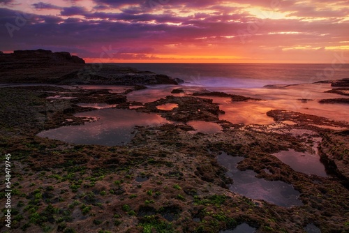 Coastal dawn skies at low tide exposing the rocky reef