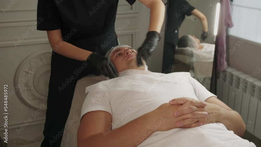 Beauty treatments - cosmetologist closes the chest of a male client with a napkin before procedures Beauty treatments - cosmetologist closes the chest of a male client with a napkin before procedures