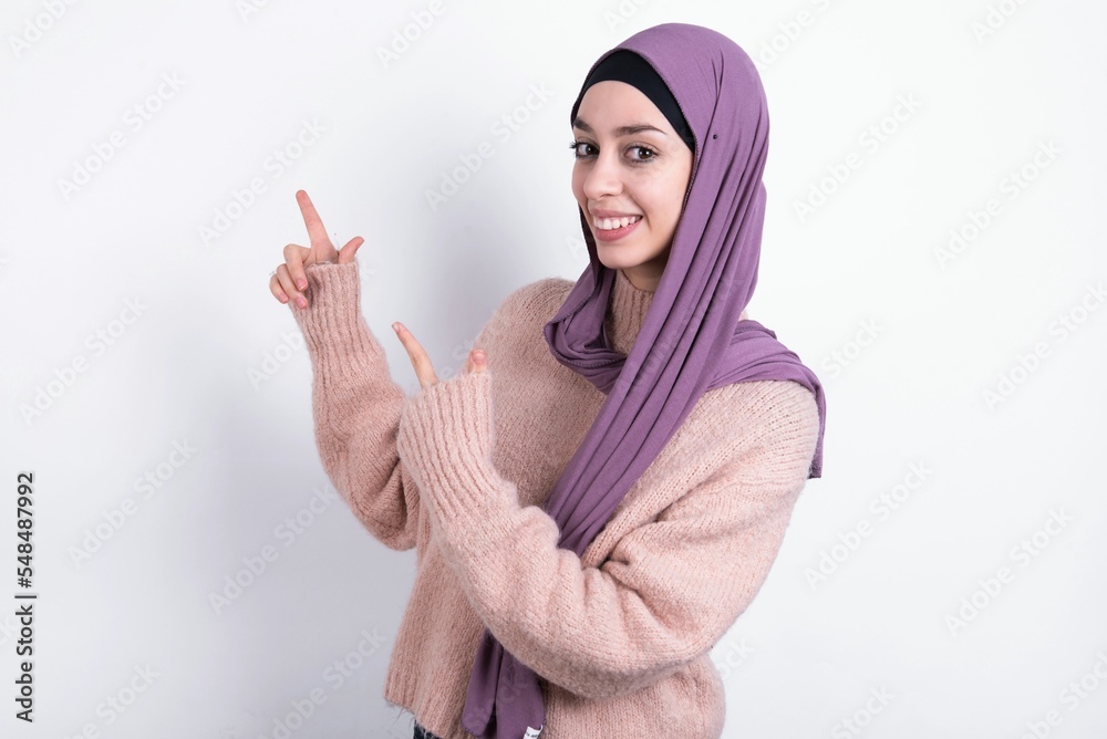 beautiful muslim woman wearing hijab and warm jumper over white background point at copyspace recommend sales discounts beautiful muslim woman wearing hijab and warm jumper over white background point at copyspace recommend sales discounts