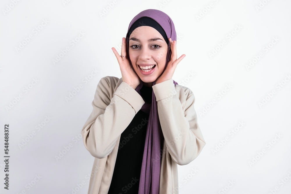 young beautiful muslim woman wearing hijab and jacket over white background Pleasant looking cheerful, Happy reaction young beautiful muslim woman wearing hijab and jacket over white background Pleasant looking cheerful, Happy reaction