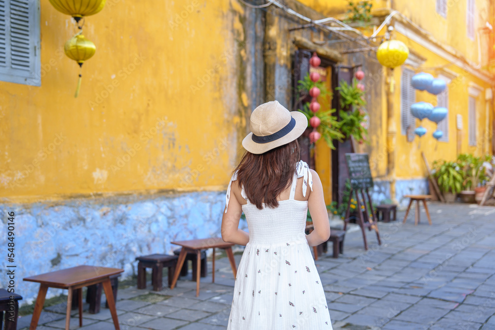 happy traveler sightseeing at Hoi An ancient town in central Vietnam, woman with dress and hat traveling. landmark and popular for tourist attractions. Vietnam and Southeast Asia travel concept