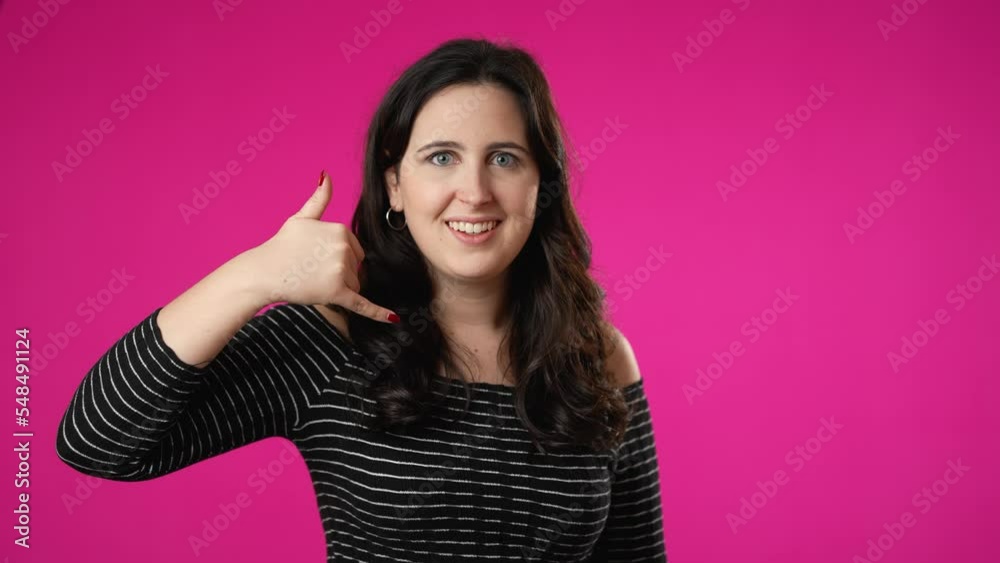 Portrait of smiling happy young woman 20s smiling and giving call me gesture with hands isolated on pink background. Portrait of smiling happy young woman 20s smiling and giving call me gesture with hands isolated on pink background.