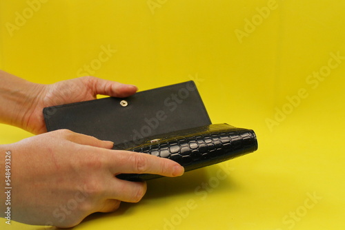 black open wallet, women's hands, yellow background