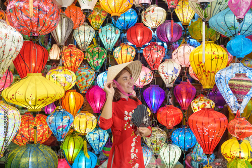 happy woman wearing Ao Dai Vietnamese dress with colorful lanterns  traveler sightseeing at Hoi An ancient town in central Vietnam.landmark for tourist attractions.Vietnam and Southeast travel concept