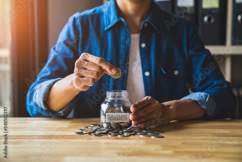 Woman puts a coin in a jar to save money for the future. after retirement and income, expenditure, savings and financial concepts