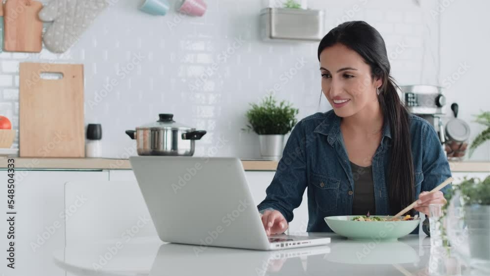 Video of cheerfull woman working with computer while with computer while eating poke bowl in the kitchen at home. Video of cheerfull woman working with computer while with computer while eating poke bowl in the kitchen at home.