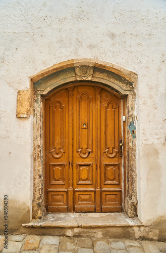 An old wooden door in a white stone building in the old town of Bratislava. High quality photo