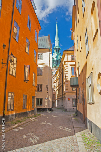Fototapeta Naklejka Na Ścianę i Meble -  Sweden - Stockholm - The view of charming narrow paved streets in old town Gamla Stan with german church (tyska kyrkan) spire in the distance