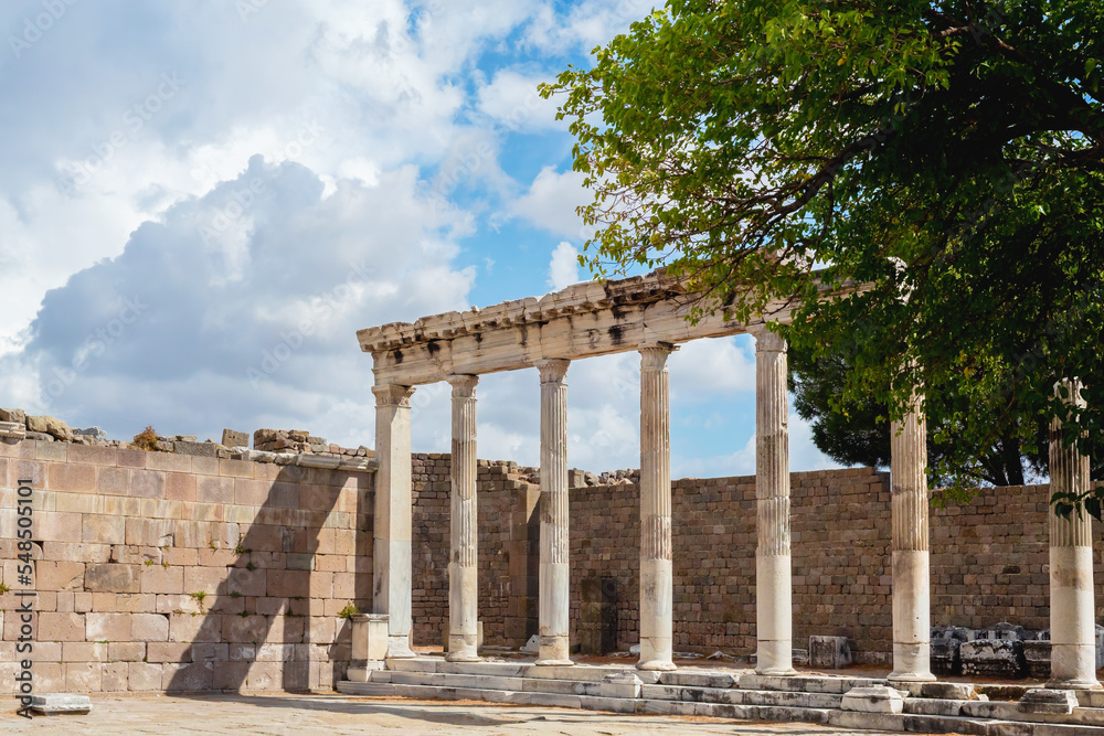 Colonnade of the ruined Temple of Trajan in Pergamon Ancient City. Corinthian order, II century AD. Beautiful clouds at background. History, art or architecture concept. Bergama, Turkey