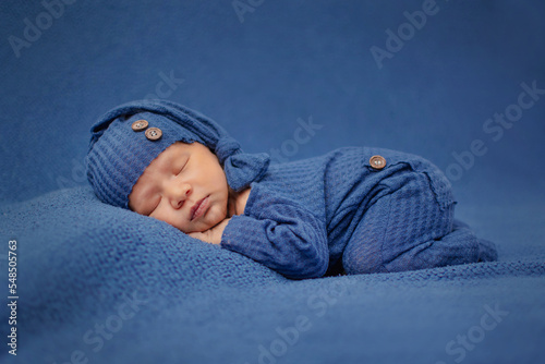 Recien nacido dormido acostado boca abajo con ropa color azul en un fondo de estudio  photo