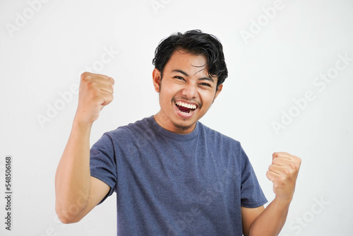 Young handsome asian man wearing casual standing over isolated white background very happy and excited doing winner gesture with arms raised, smiling and screaming for success. Celebration
