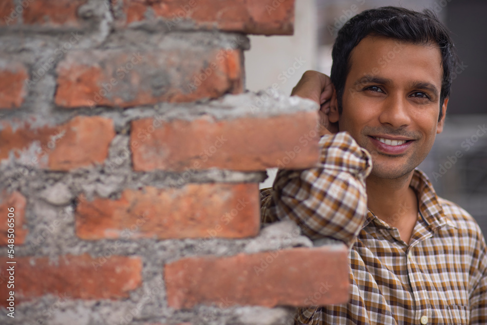 Close-up portrait of smiling young man leaning on brick wall Close-up portrait of smiling young man leaning on brick wall