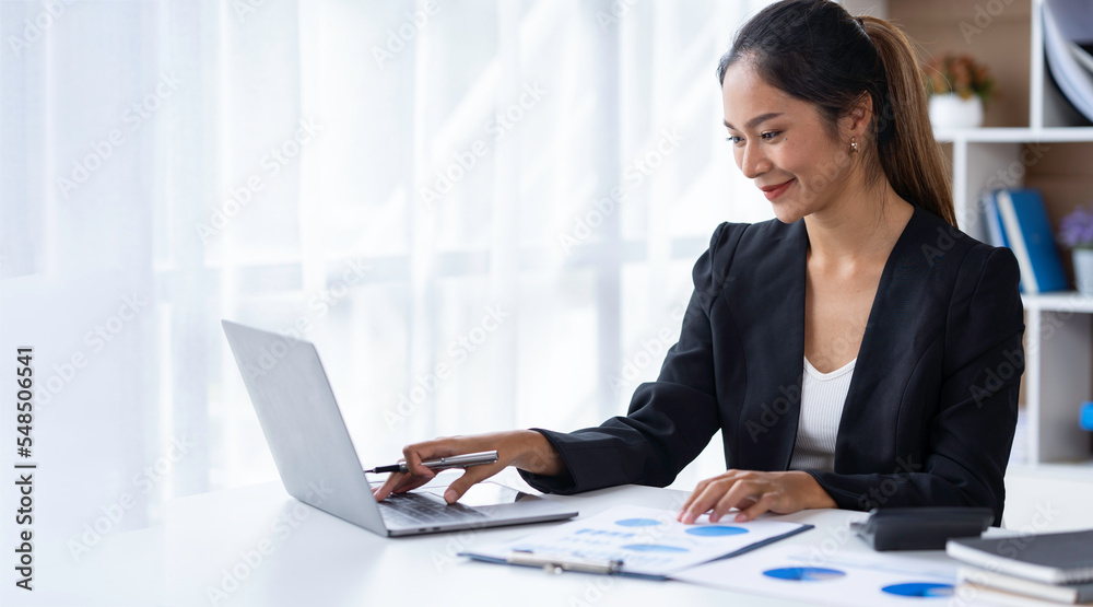 Attractive and confident, successful Asian businesswoman sitting on her laptop in the office. Attractive and confident, successful Asian businesswoman sitting on her laptop in the office.