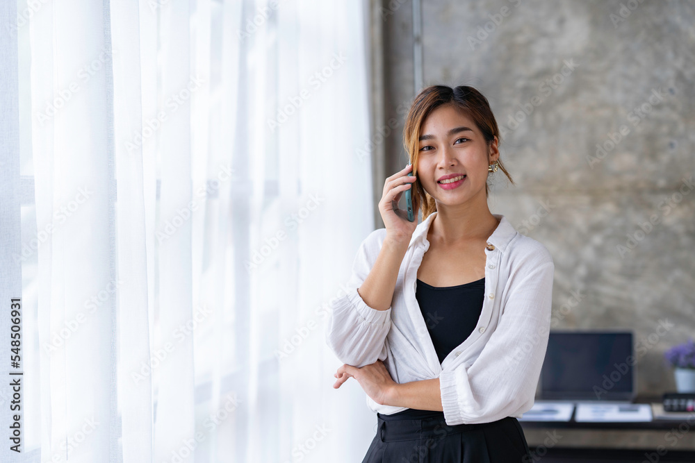 Beautiful and cute Asian business woman Office workers stand on the phone to talk and answer questions from customers in the office. Beautiful and cute Asian business woman Office workers stand on the phone to talk and answer questions from customers in the office.