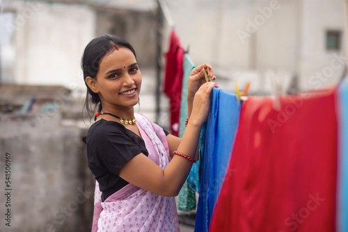Woman hanging out wet clothes on washing line in the backyard