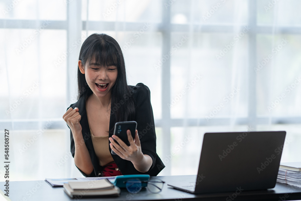 Asian businesswoman in formal suit in office happy and cheerful during using smartphone and working Asian businesswoman in formal suit in office happy and cheerful during using smartphone and working