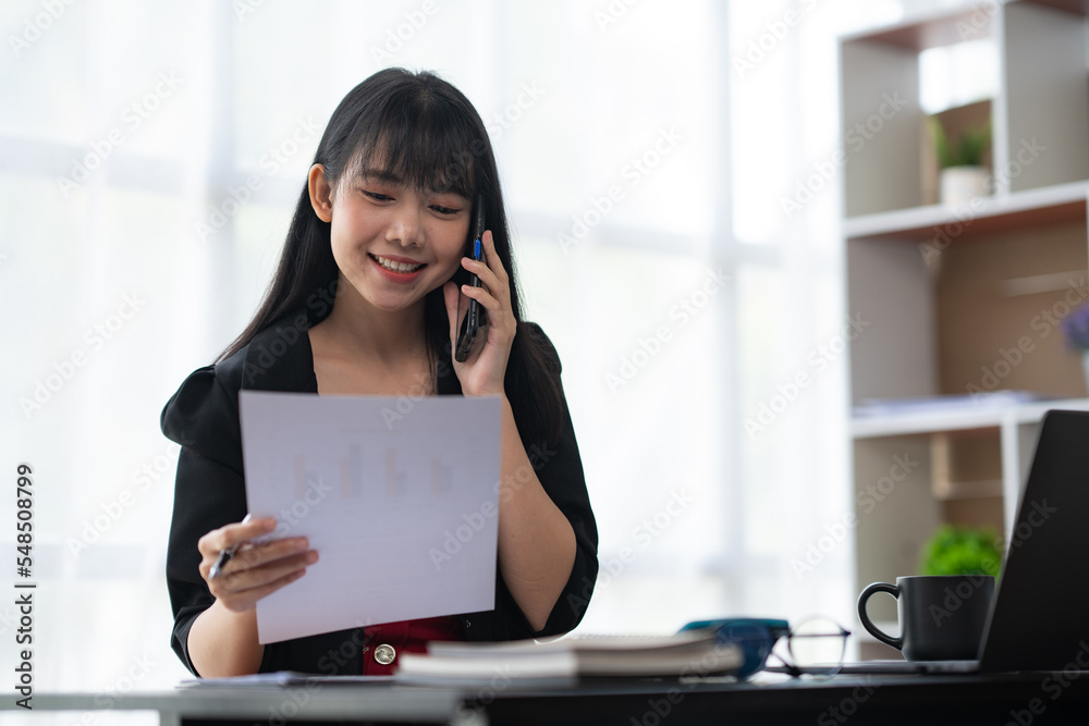 Asian businesswoman in formal suit in office happy and cheerful during using smartphone and working Asian businesswoman in formal suit in office happy and cheerful during using smartphone and working