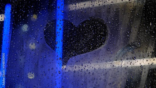 A heart drawn on a misted night window on a rainy day, close-up. Love, falling in love, depression, unrequited love concept photo
