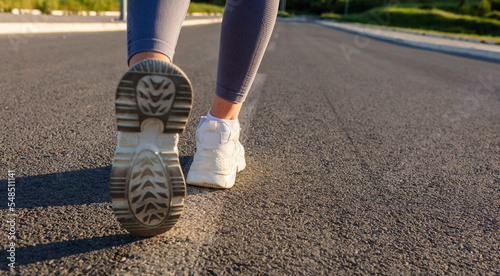 Closeup shot of an unrecognisable woman running outdoors. Photo of female jogging away from camera on a jog path early in the morning.